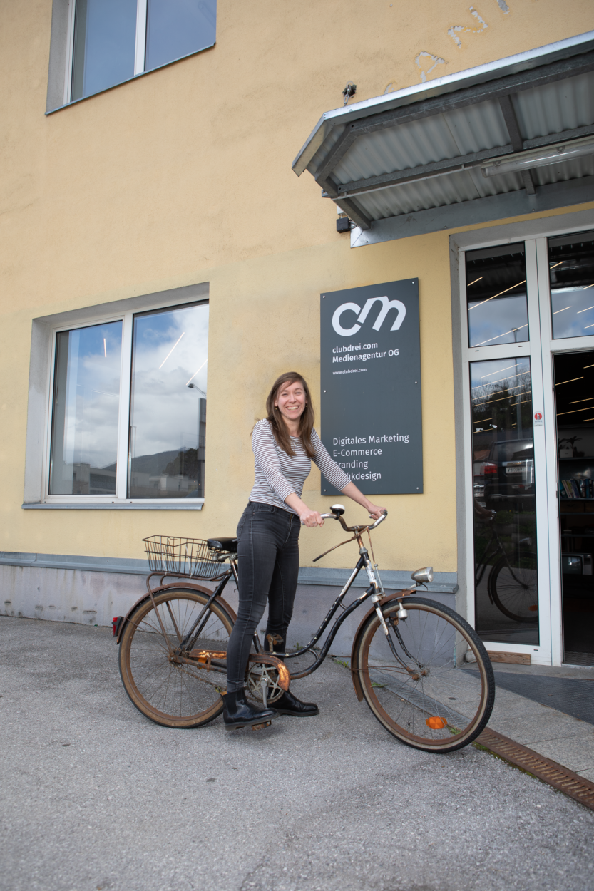 Eine lächelnde, weibliche Person mit einem alten Fahrrad