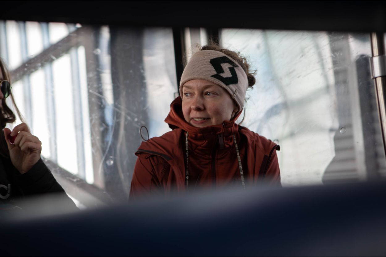 Anna sitzt in Winterkleidung in einer Gondel und lächelt