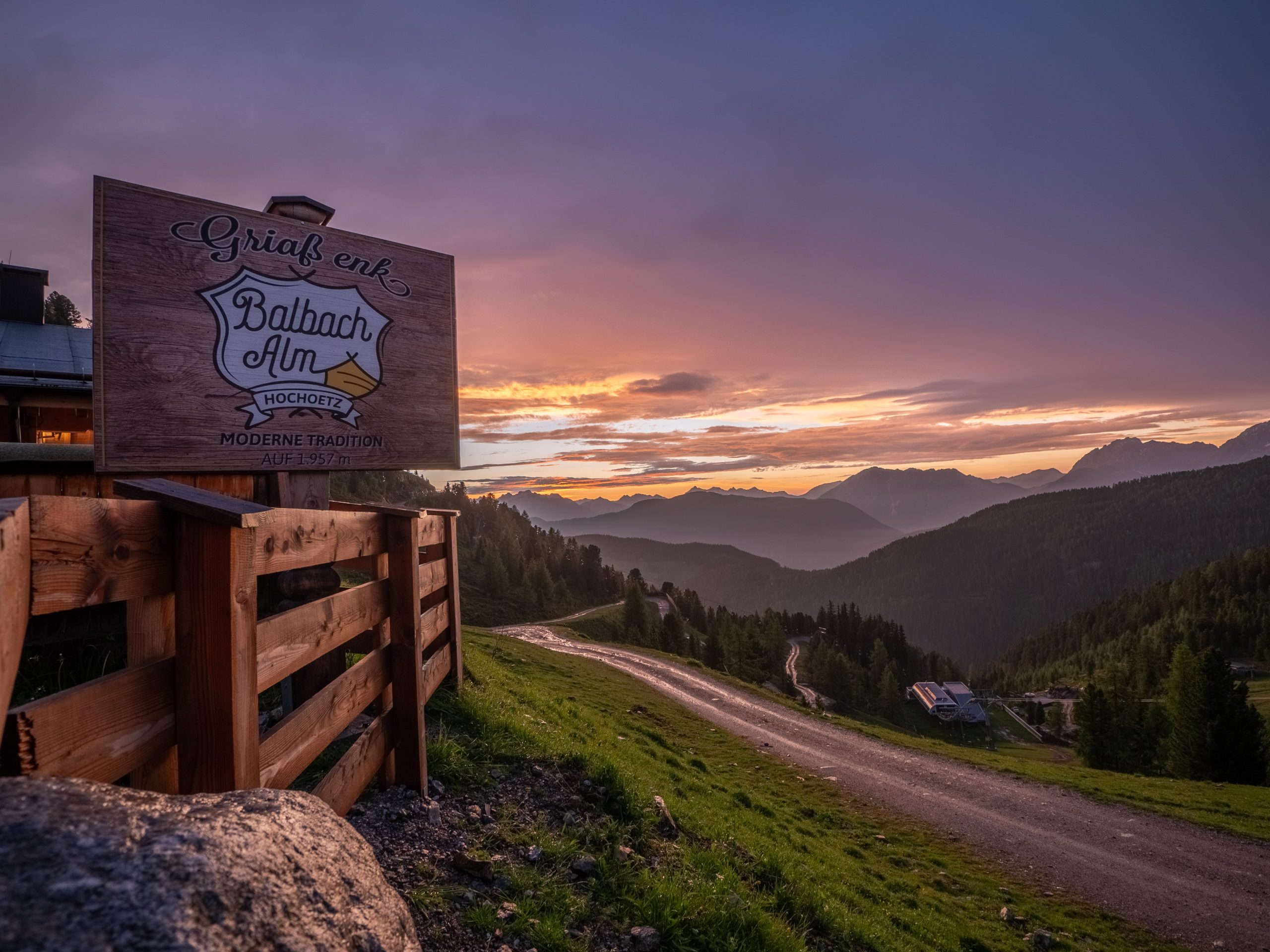 Das Balbach Alm Schild vor einer Bergkulisse im Sonnenuntergang