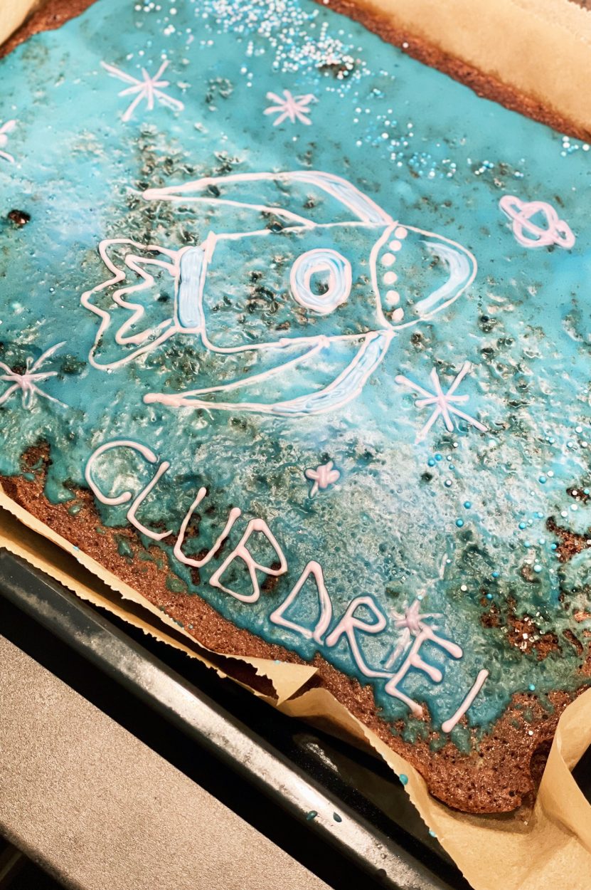 Ein Blech mit Kuchen mit einer Rakete und clubdrei Schrift